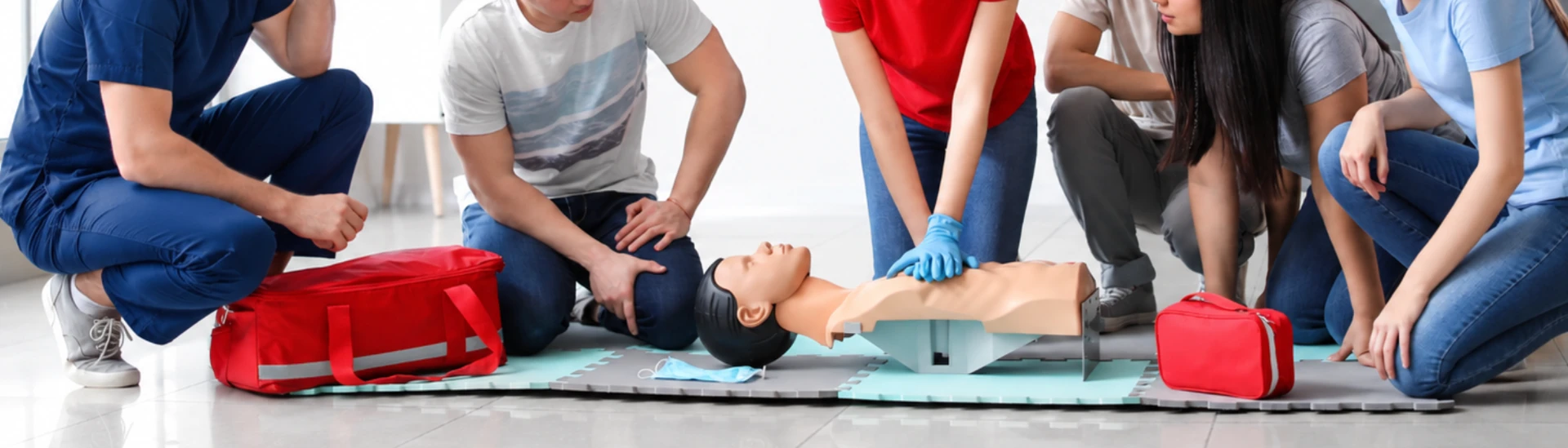 A group practising CPR on a mannequin with first aid equipment