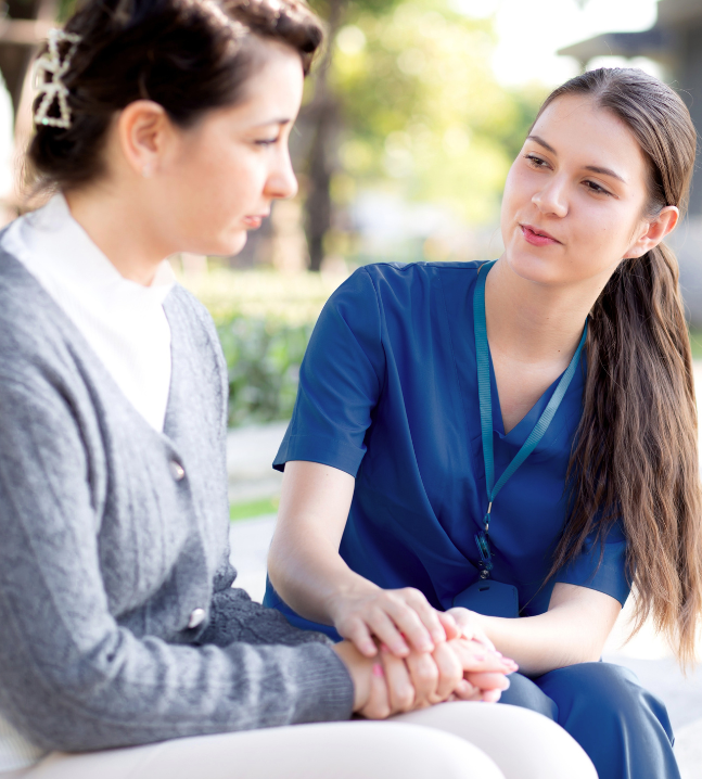 A caregiver listening and offering reassurance to a woman outdoors